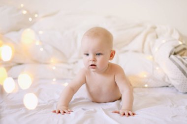 Karnını doyuran küçük bir çocuk. Sevimli bebek beyaz yatak odasında emeklemeyi öğreniyor. Yatakta yatan sevimli komik bebek.. 