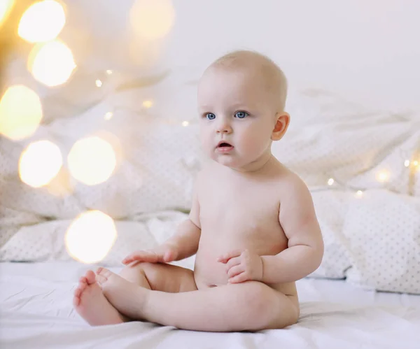 Carino bambino sorridente siede sul letto. felice bambino nudo. bambini di età inferiore a un anno. bambina che gioca, sorride, posa sul letto — Foto Stock