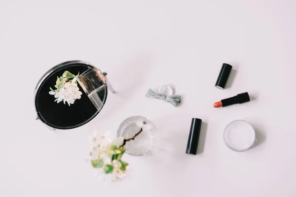 Flores de flor, cosméticos e um espelho na vista superior da mesa de vestir. Flat lay com acessórios para mulheres. Composição cosmética . — Fotografia de Stock