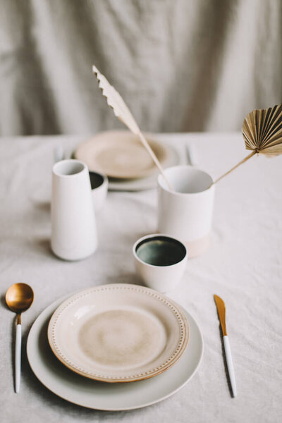 Elegant table setting for fine dining with cutlery, plates, cups on a linen tablecloth. Home decor rustic table setting