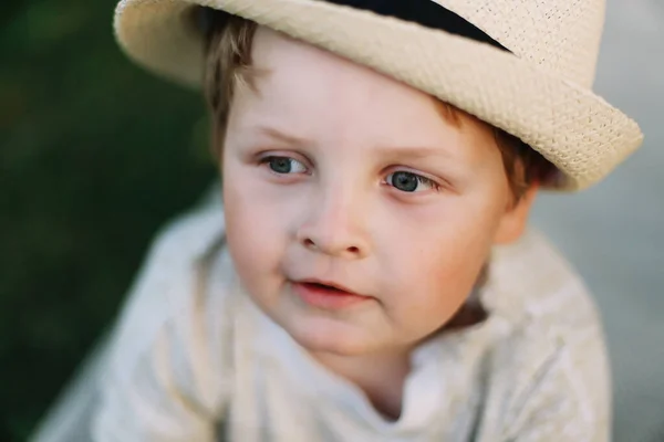 Közelkép egy mosolygó fiúról a szabadban. Egy gyönyörű, aranyos fiú kalapban. — Stock Fotó