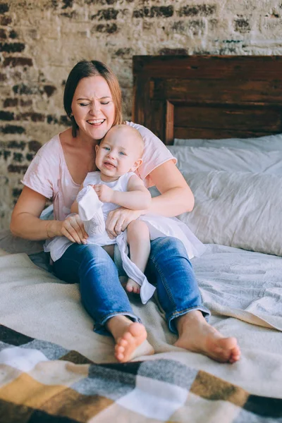 Mãe veste a filha, em um vestido branco e meia-calça — Fotografia de Stock