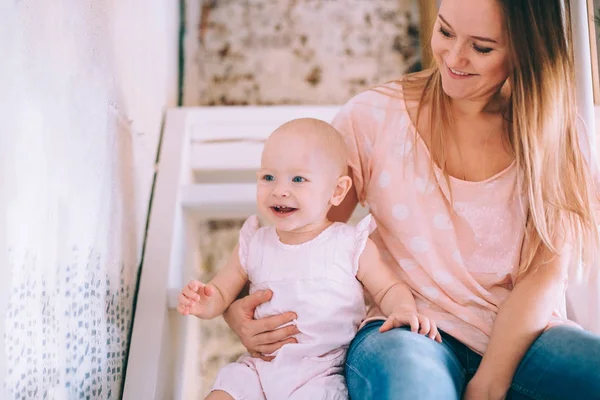 En ung mamma med ett litet barn som sitter på en trätrappa — Stockfoto