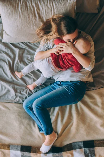 Uma jovem mãe com ela com uma criança pequena, deitada na cama vista de cima — Fotografia de Stock