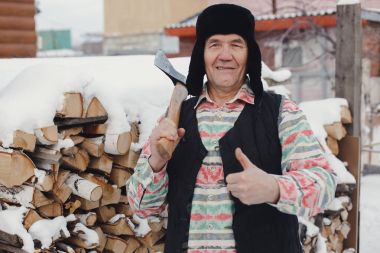 Elinde bir balta ile yaşlı adam gülümsüyor