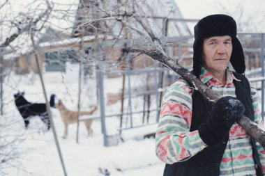 Bir adam bir ağaç dalı omzunda tutar.