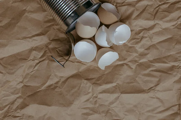 Eggshell in tin top view. Creative still life photo of an Eggshell in a tin can on brown background.