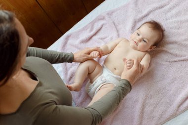 Anne ve tatlı çocuğunun yataktaki en güzel görüntüsü. Bebek masajı ve jimnastik egzersizleri..