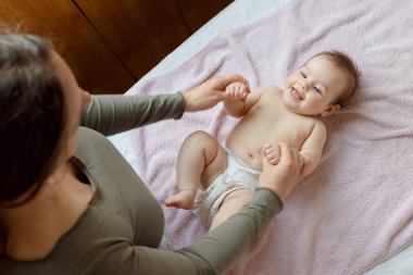 Anne ve tatlı çocuğunun yataktaki en güzel görüntüsü. Bebek masajı ve jimnastik egzersizleri..