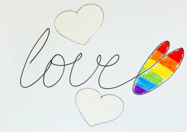 Aşk kelimesi siyah kalemle yazılmıştır. Beyaz üzerine Lgbt bayraklı gökkuşağı kalp şeklinde bir kalp çizilmiştir. Onur Günü kavramı, Sevgililer Günü, özgürlük, aşk.