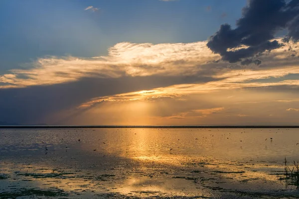 Golden sunset bulvarında bir göl fırtına karanlık bulutlar ve sun ray ile sonra