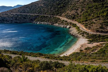 Çakıl plajı ile berrak mavi suları açık gökyüzü altında küçük bir koyda