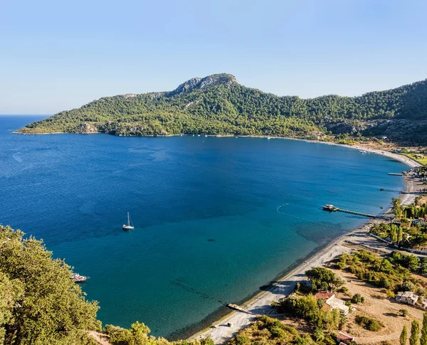Güzel bay turkuaz suları ile kumlu plaj altında yeşil tepelerle çevrili açık mavi gökyüzü