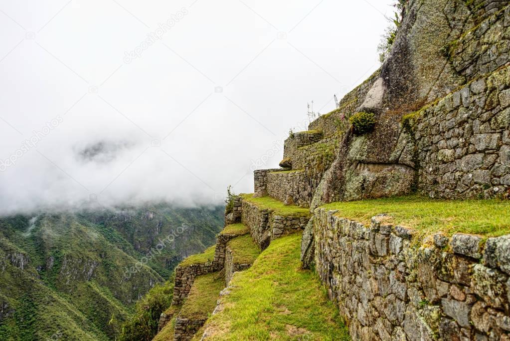 Green agricultural terraces of ancient Inca Citadel under heavy fog