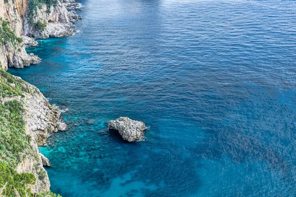 Turkuaz renkli suların içinde bir kaya ile Capri Adası defne