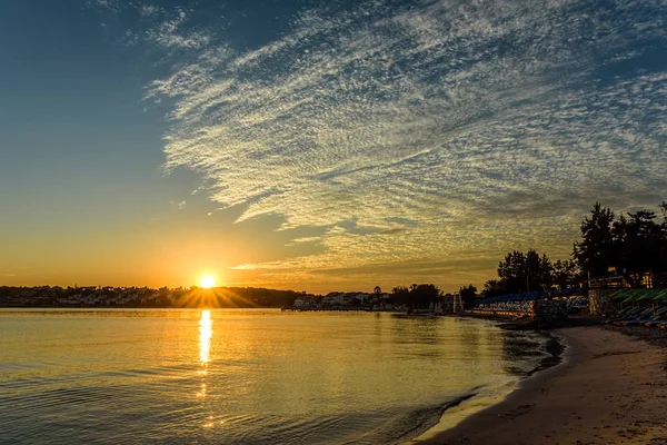 Схід сонця з розсіяними білими хмарами на золотому блакитному небі — стокове фото