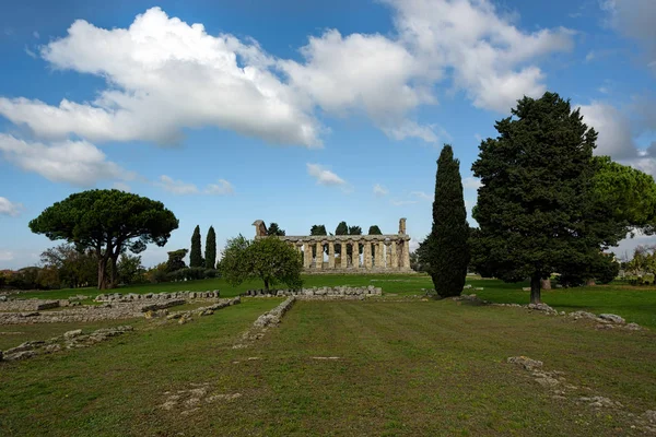 Bir tapınak ve açık mavi gökyüzü altında koyu yeşil ağaçlar