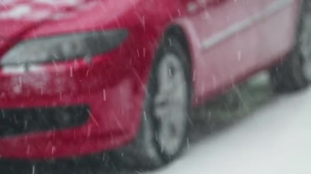 Снігопад на тлі червоний автомобіль. розмитість фону — стокове відео