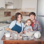 Young family preparing cookies in shape of christmas tree