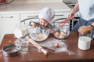 mother and laughing happy child preparing dough at kitchen