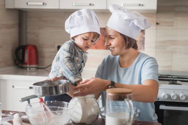 mutlu anne ve dağınık mutfak masasında hamur hazırlama chef şapka içinde çok güzel çocuk