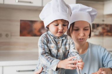 Anne ve sevimli çocuk chef şapka birlikte mutfak yemek