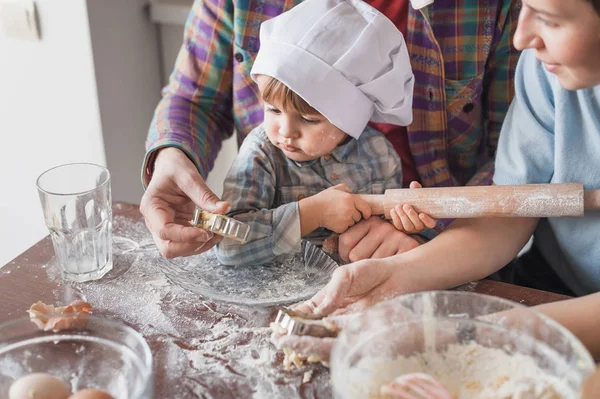 両親とクッキーの生地を準備するシェフ帽子でかわいい子供 — ストック写真