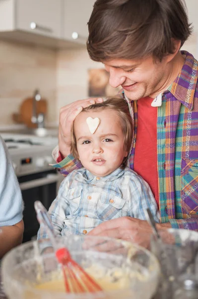 father and child with cookie in shape of heart on forehead