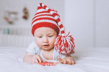 bebek çocuk oyuncak yatakta bakarak kırmızı ve beyaz çizgili şapkalı