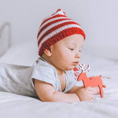 yakın çekim yatakta oyuncak geyik ile oynarken örme çizgili şapkalı bebek çocuk portresi