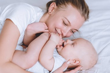 close-up shot of mother and her infant baby cuddling in bed clipart