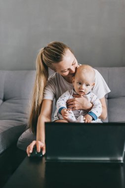 evde kanepede genç anne ve bebek çocuk otururken dizüstü'nın birlikte kullanılması