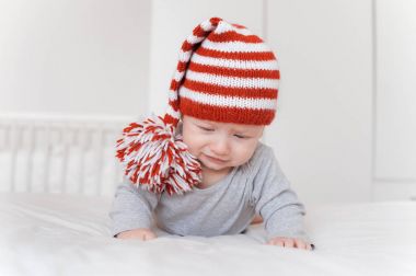 yatakta yatarken ve aşağı bakıyor örgü şapkalı küçük bebek çocuk portresi