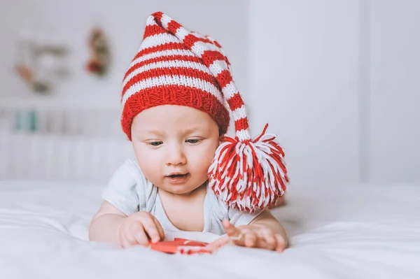 Немовля Червоно Білому Смугастому Капелюсі Дивиться Іграшку Ліжку — стокове фото