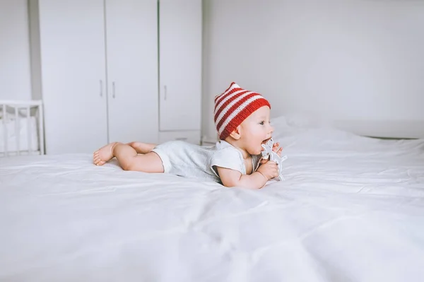 Немовля Червоно Білій Смугастій Шапці Помпоном Грає Іграшковим Оленям Ліжку — стокове фото