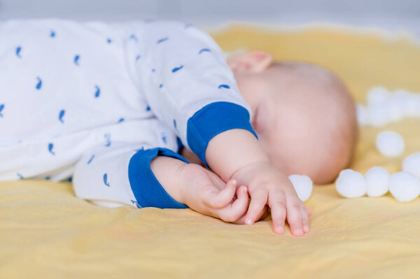Крупный план младенца, спящего в постели в окружении ватных шариков
