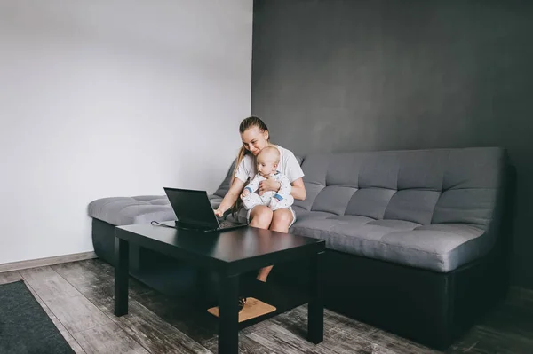 Молода Мати Працює Ноутбуком Сидячи Дивані Своєю Дитиною — стокове фото