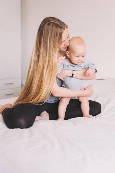 Beautiful Young Mother Hugging Adorable Little Child While Sitting Bed — Stock Photo, Image