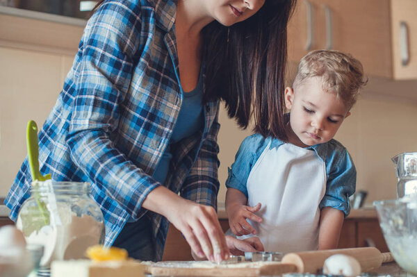 cropped image of mother making cookies with dough molds