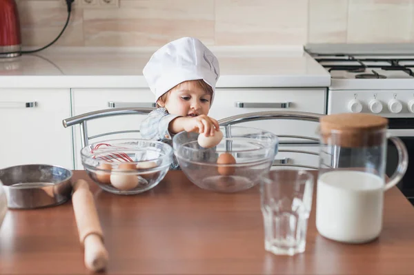 Cute little kid in chef hat cooking at kitchen — Stock Photo