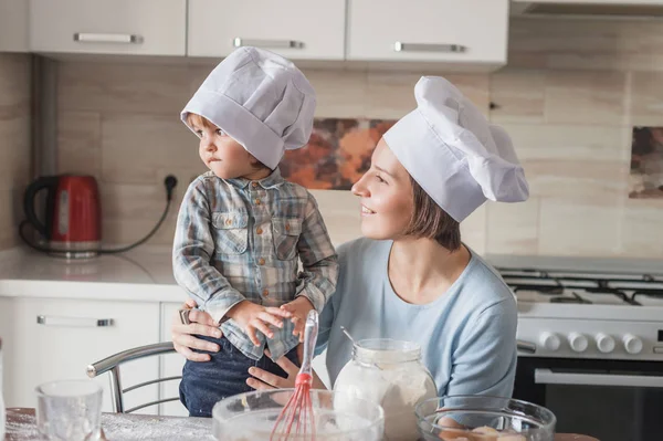 Mère et enfant regardant loin tout en préparant la pâte à la cuisine — Photo de stock