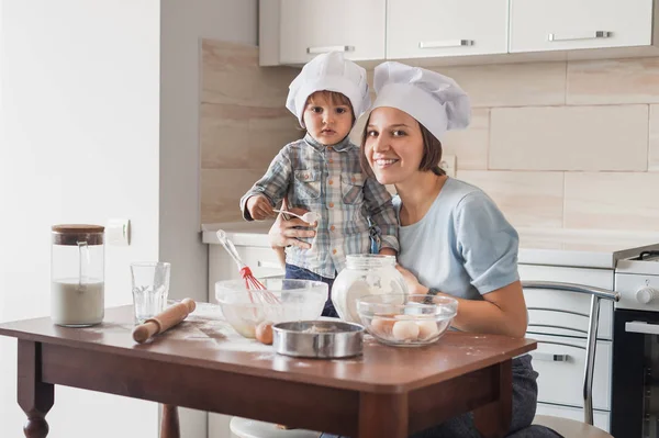Mère et enfant préparant la pâte à la cuisine et regardant la caméra — Photo de stock
