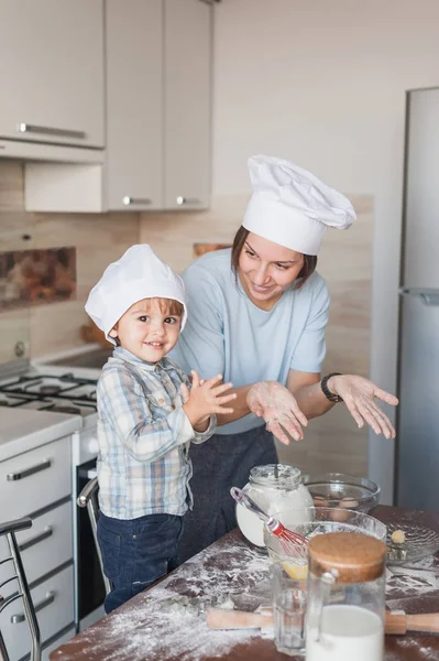 Glückliche junge Mutter und Kind beim Teigzubereiten in der Küche — Stockfoto