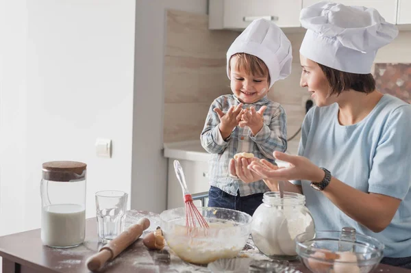 Mãe bonita feliz e criança que prepara a massa de farinha na cozinha — Fotografia de Stock