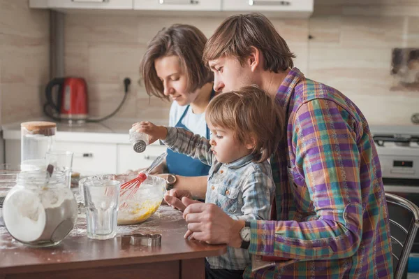 Beautiful young family making dough at kitchen — Stock Photo