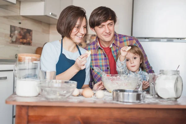 Familia joven y feliz preparando galletas caseras en forma de corazones - foto de stock