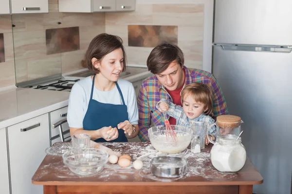 Hermosa familia joven preparando galletas caseras en forma de corazones - foto de stock