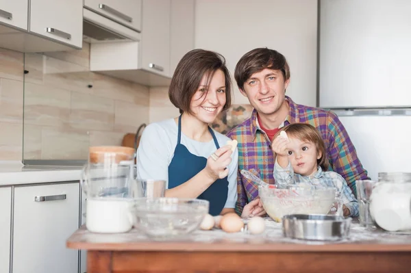 Familia joven preparando galletas caseras en forma de corazones - foto de stock