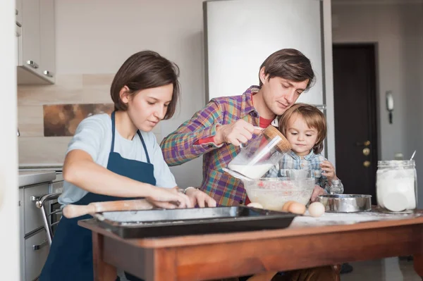 Hermosa familia joven preparando masa para galletas caseras - foto de stock