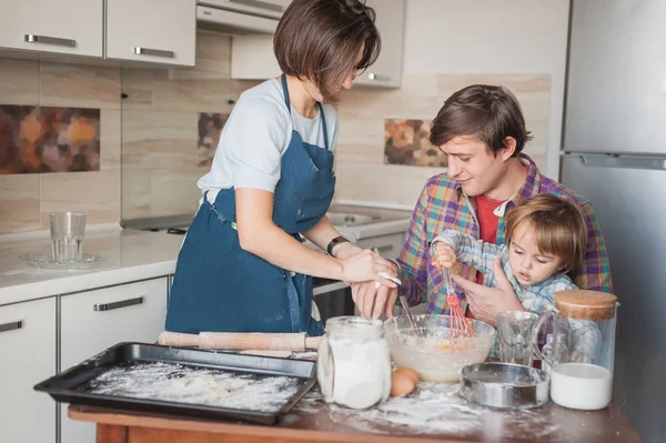 Bela jovem família preparando biscoitos caseiros juntos — Fotografia de Stock